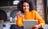 Femme souriante tenant une carte-cadeau tout en tapant sur son ordinateur portable